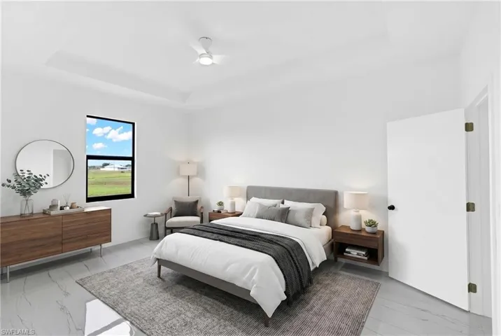 Spacious room featuring a tray ceiling with a ceiling fan, a window with dark framing, light-toned walls, and large format tile flooring