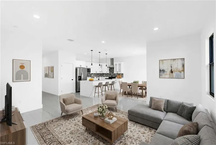 Expansive open-concept living area featuring white walls and light-toned flooring