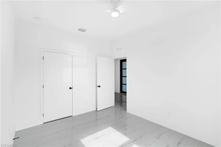 Bright interior space featuring white walls, patterned tile flooring, and a ceiling fan with integrated lighting