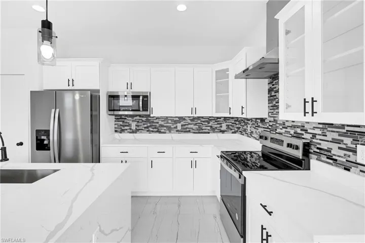 Contemporary kitchen featuring white cabinetry, stainless steel appliances, a mosaic tile backsplash, white countertops, and wood-finish flooring