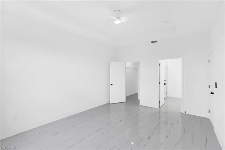 Room featuring white walls, large format tile flooring with subtle veining, recessed lighting, and a ceiling fan