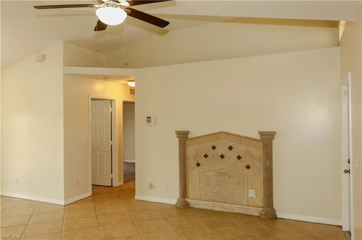 Spare room featuring ceiling fan, lofted ceiling, and light tile patterned flooring