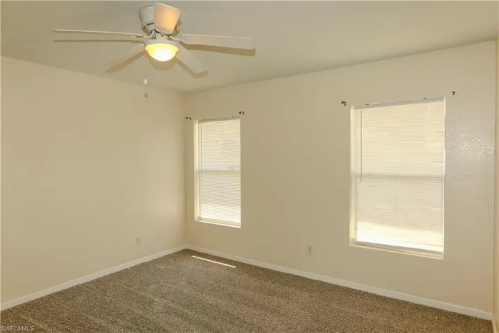 Empty room with dark carpet and ceiling fan