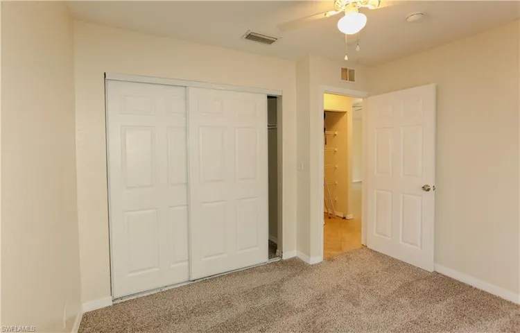 Unfurnished bedroom with a closet, light carpet, and a ceiling fan