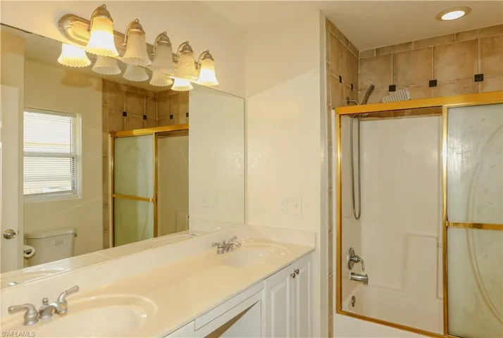 Full bath featuring double vanity and enclosed tub / shower combo