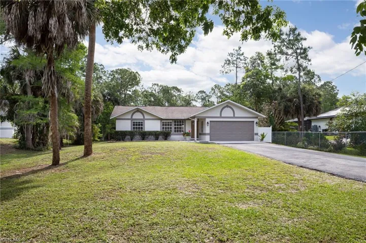 The property features a well-maintained lawn, a paved driveway, and updated landscaping