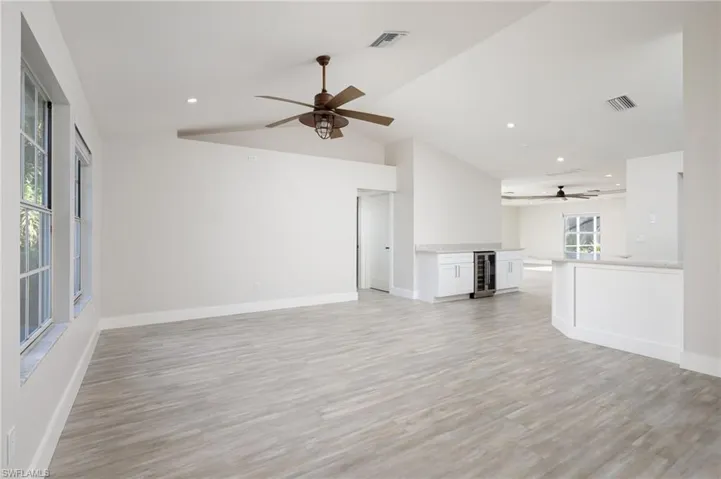 Expansive interior with light wood-style flooring, white walls, and vaulted ceilings