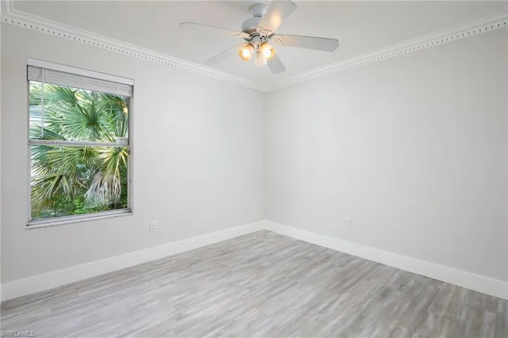 This guest bedroom features light-colored walls, crown molding, new baseboard & trim and wood-look luxury vinyl flooring