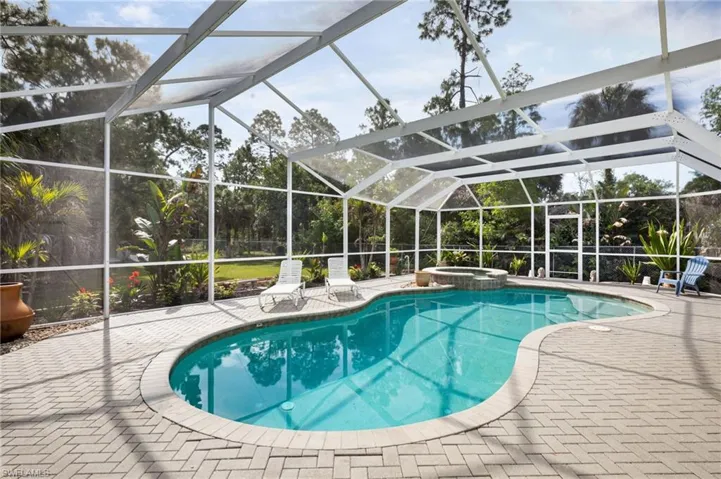 The property features a screened-in pool area with a freeform pool and an integrated spa
