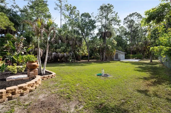 Expansive yard featuring a well-maintained lawn, a retaining wall with landscaping, and a shed