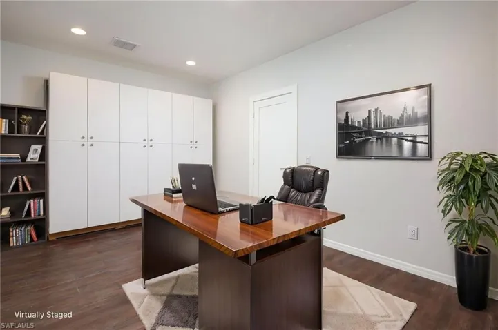 This bonus room features dark wood flooring, recessed lighting, and a wall of white storage cabinets. This flex room could be used as an office/den, fitness room, hobby room, library, etc.