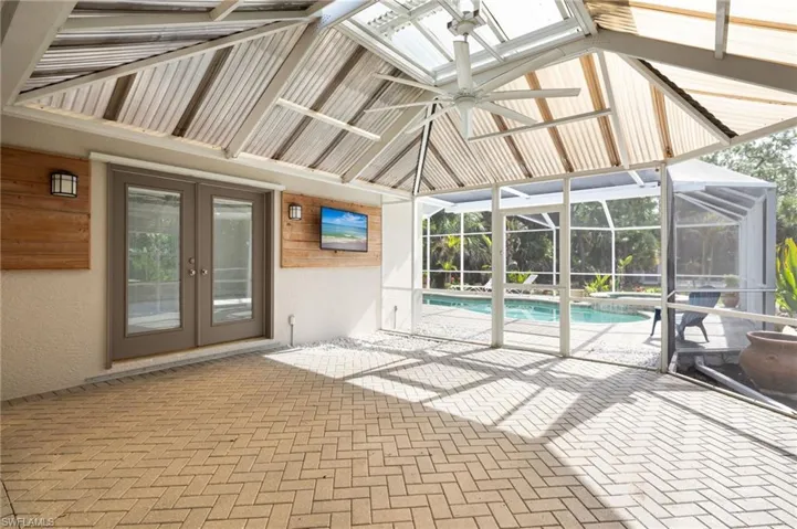 The screened lanai features a paver patio, a ceiling fan, and access to a swimming pool