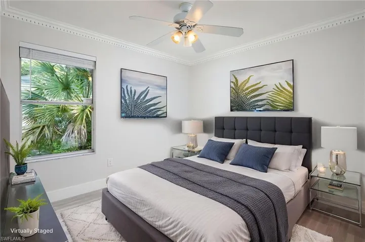 This guest bedroom features light-colored luxury vinyl flooring, new baseboards, trim and interior door, crown molding, and a ceiling fan with integrated lighting