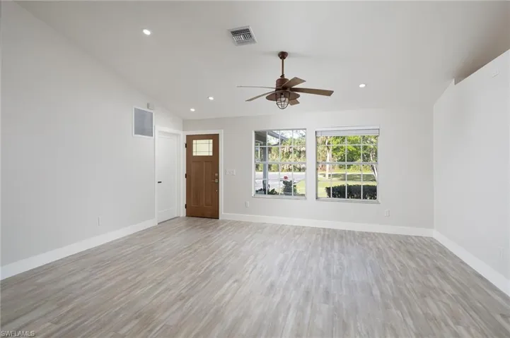 The living area features light-toned flooring, white walls, and a ceiling fan with an integrated light fixture