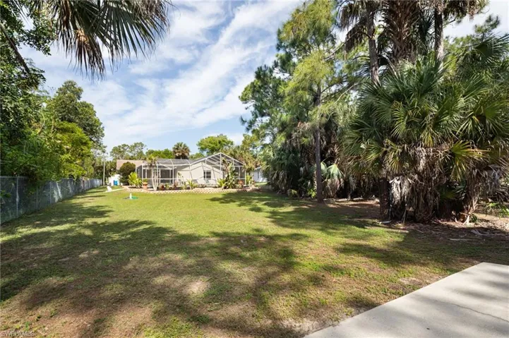 Expansive yard with mature trees and a chain link fence