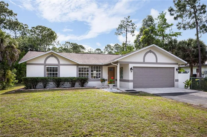 The property features a well-maintained exterior with a white facade and gray trim and a lush green lawn