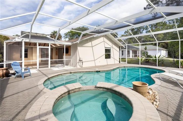 The property features a screened-in pool and hot tub, set on a brick paver deck