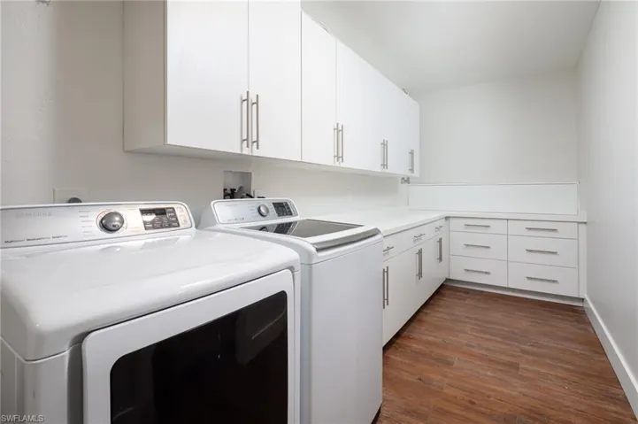 Well-appointed utility room featuring Samsung washer and dryer, white cabinetry, light countertops, and wood-look flooring