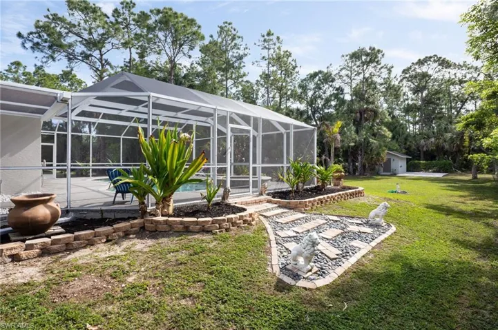 The property features a screened-in pool enclosure, a well-maintained lawn, and mature trees