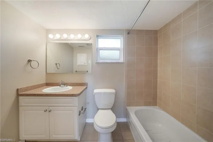 Full bath with light tile patterned flooring, vanity, and shower / bath combination