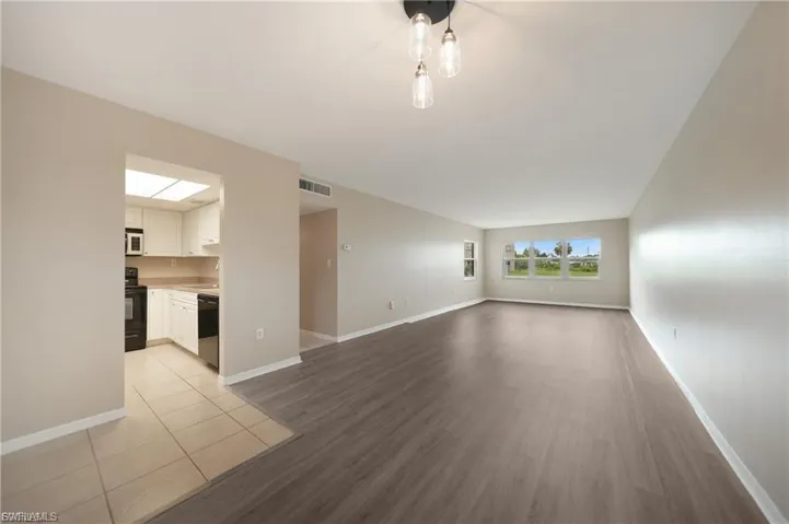 Unfurnished living room with light wood-style floors and baseboards