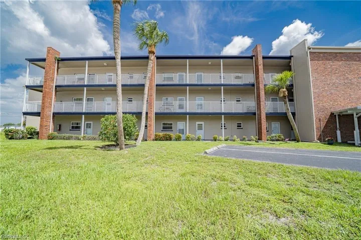 View of apartment building / complex with uncovered parking