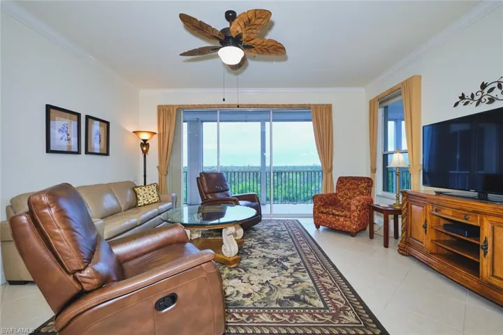 Living area with ornamental molding, light tile patterned flooring, and ceiling fan