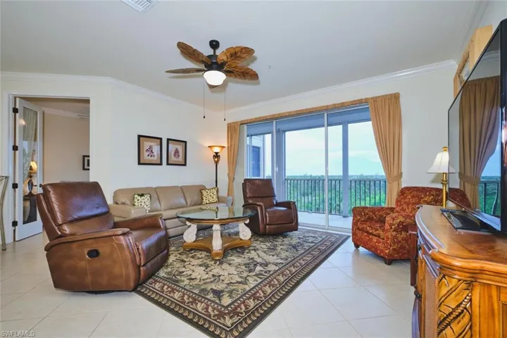 Living area with ornamental molding, light tile patterned flooring, and ceiling fan