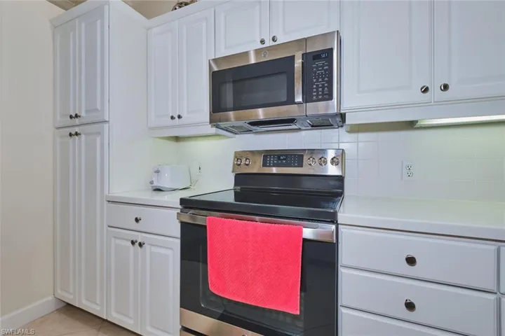 Kitchen featuring white cabinetry, appliances with stainless steel finishes, light countertops, and tasteful backsplash