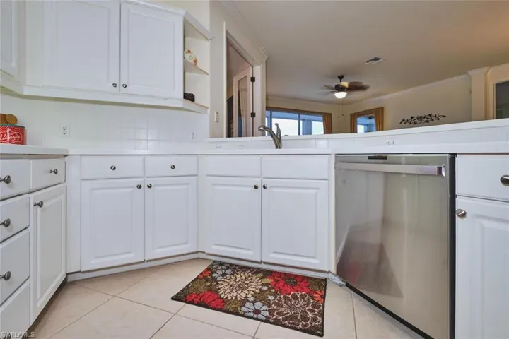 Kitchen with white cabinets, dishwasher, light countertops, light tile patterned flooring, and open shelves