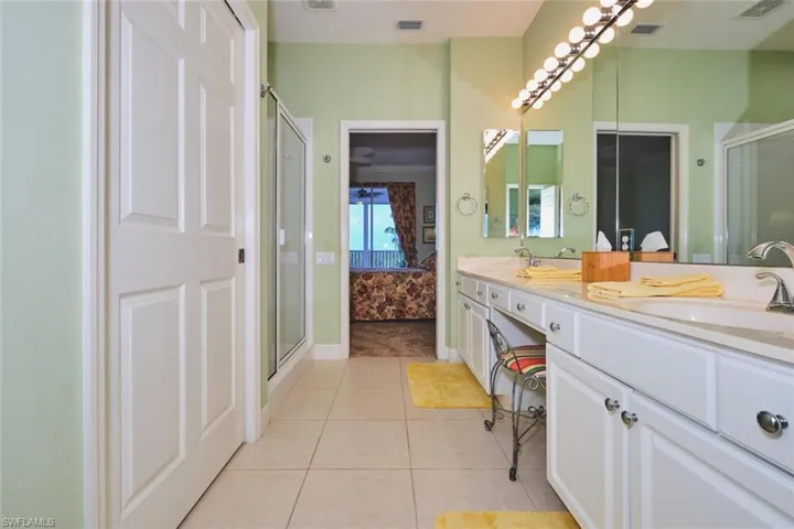 Ensuite bathroom with a stall shower, double vanity, and light tile patterned floors
