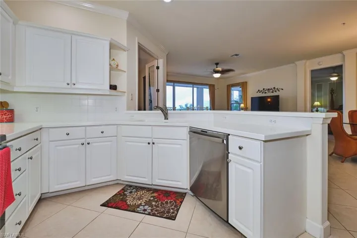 Kitchen featuring white cabinets, light tile patterned flooring, a peninsula, open shelves, and ornamental molding
