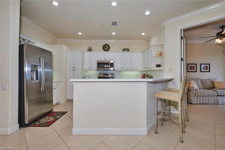 Kitchen featuring stainless steel appliances, white cabinets, crown molding, open shelves, and light tile patterned floors
