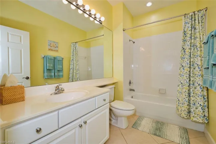 Full bath with shower / tub combo, light tile patterned flooring, and vanity
