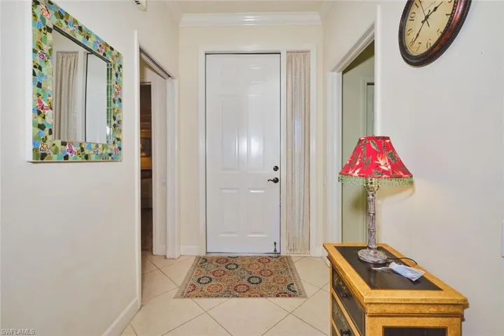 Foyer with light tile patterned floors and ornamental molding