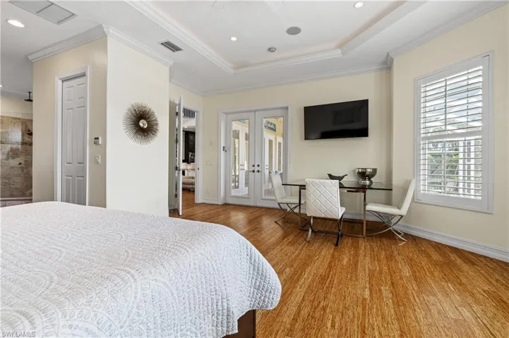 Primary Bedroom with crown molding, wood finished floors, french doors, access to lanai