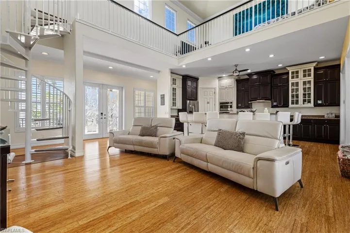 Living area featuring recessed lighting, light wood-type flooring, a towering ceiling, and french doors