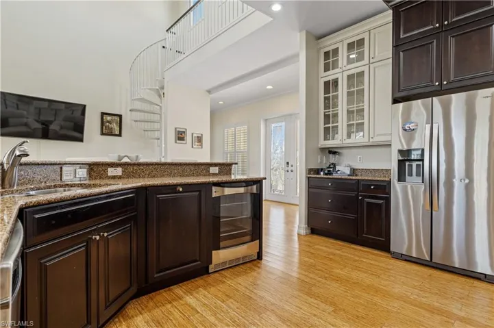 Kitchen with light wood finished floors, wine cooler, a sink, dark brown cabinetry, and appliances with stainless steel finishes