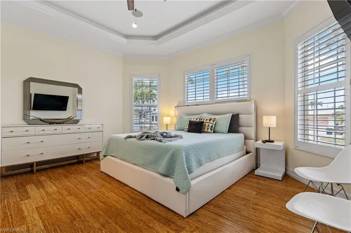 Bedroom featuring crown molding, a tray ceiling, and wood finished floors