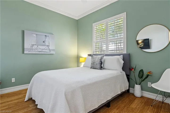 Bedroom featuring wood finished floors and crown molding