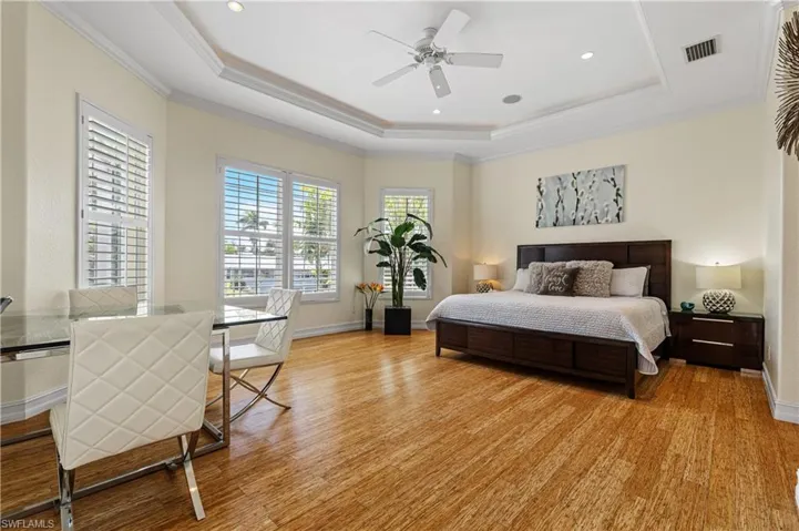 Bedroom featuring a tray ceiling, crown molding, and light wood-style flooring