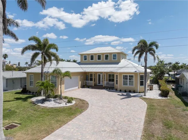 View of front of house featuring a porch, paver driveway, and a side-load garage