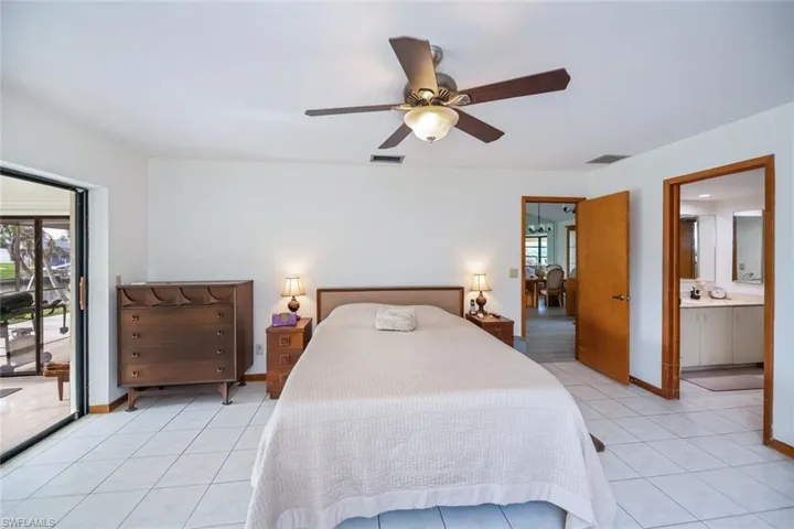 Bedroom with access to outside, light tile patterned floors, ceiling fan, and connected bathroom