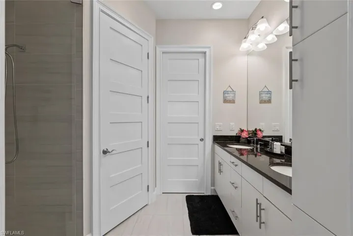 Primary Ensuite bathroom with double vanity, light tile patterned flooring, and a walk-in tile shower