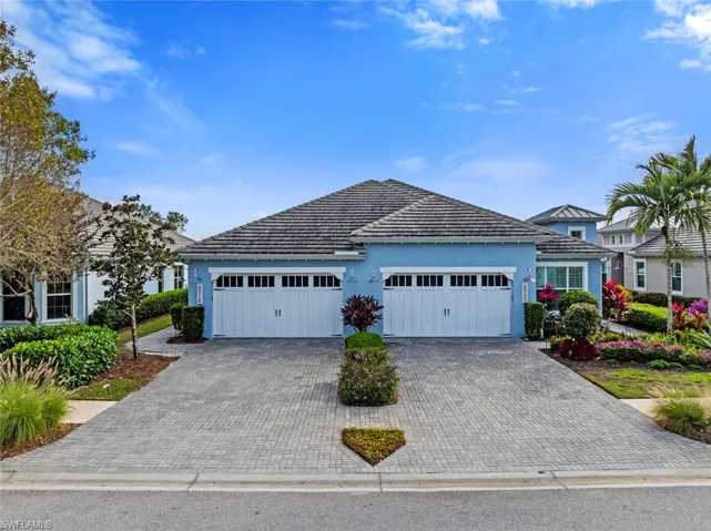 View of front facade featuring paver driveway, and a garage