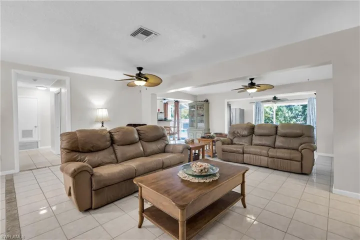 Living area with light tile patterned flooring, a textured ceiling, ceiling fan, and visible vents