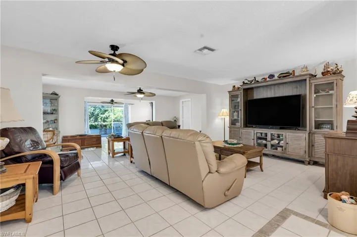Living area featuring light tile patterned floors, visible vents, and a ceiling fan