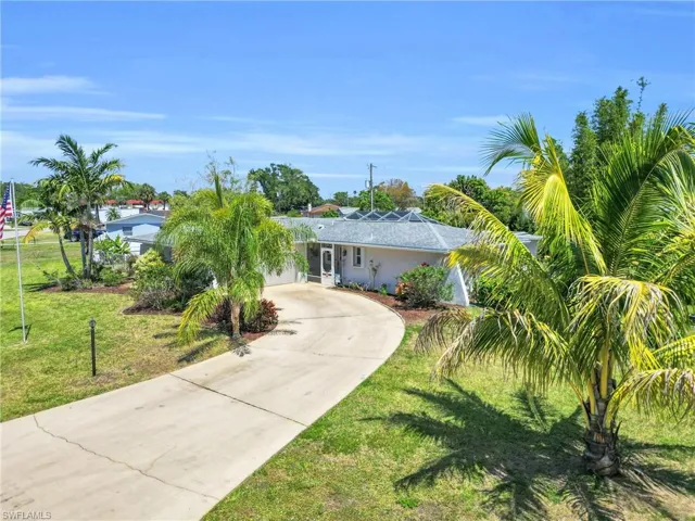 View of front of house featuring stucco siding, a front lawn, and curved driveway