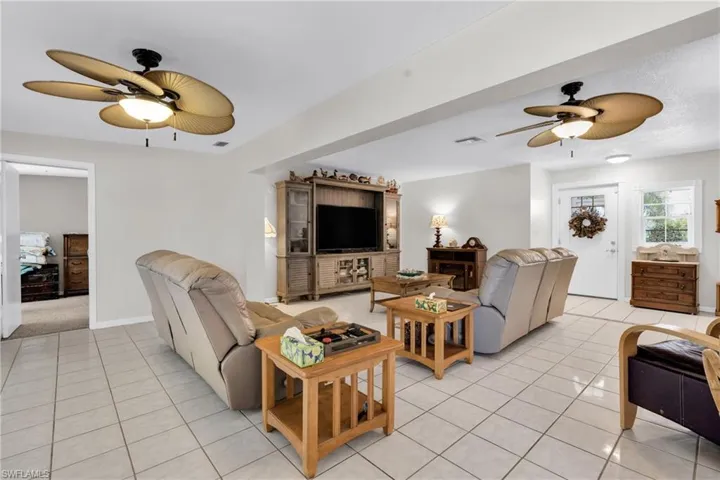 Living area featuring light tile patterned flooring, baseboards, a ceiling fan, and visible vents