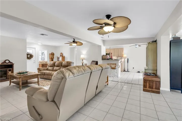 Living area featuring light tile patterned floors, baseboards, a ceiling fan, and visible vents